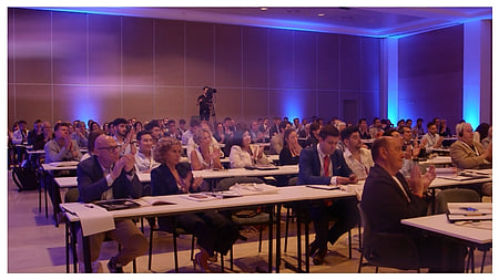 Asistentes a un congreso en una sala iluminada de azul
