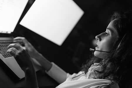 Mujer con auriculares y micrófono trabajando con un portátil